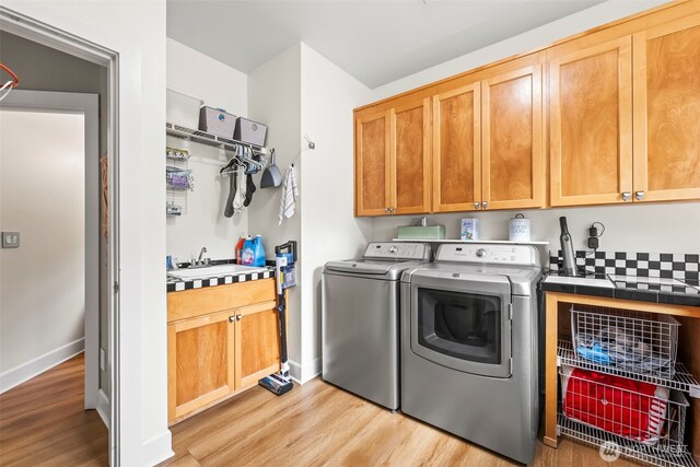 471 Dungeness Dr, Fox Island, WA 98333 - washroom featuring cabinet space, washing machine and clothes dryer, light wood-style flooring, and baseboards