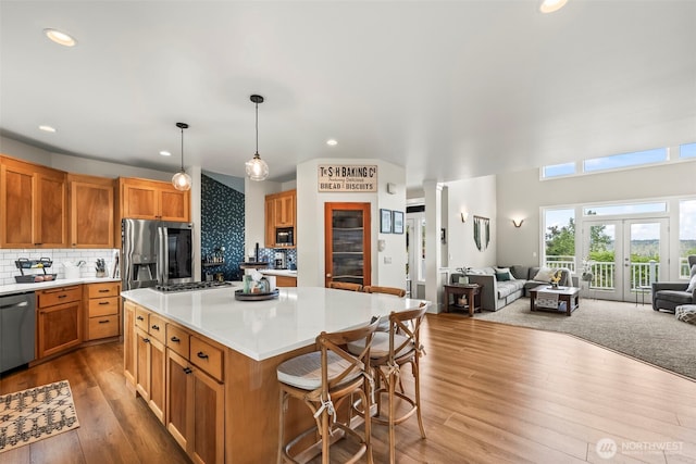 471 Dungeness Dr, Fox Island, WA 98333 - kitchen featuring stainless steel appliances, open floor plan, wood finished floors, a kitchen island, and a breakfast bar area