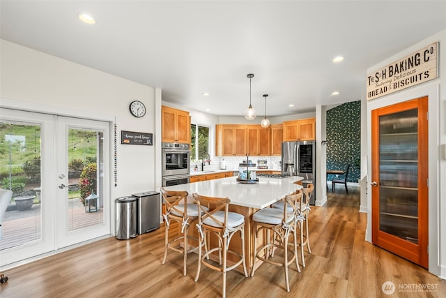 471 Dungeness Dr, Fox Island, WA 98333 - kitchen featuring stainless steel appliances, french doors, a sink, a breakfast bar area, and light wood-style flooring