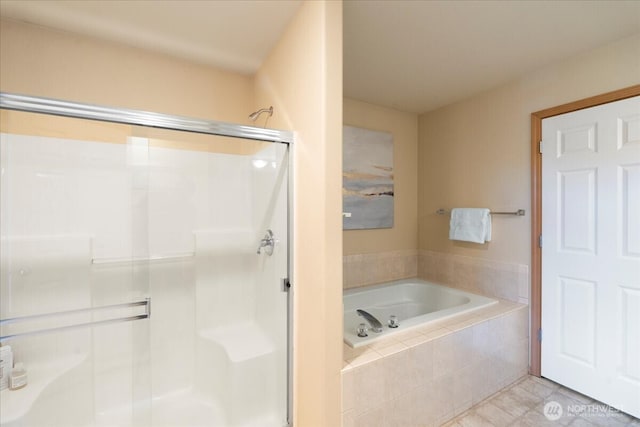 full bathroom featuring a stall shower, a bath, and tile patterned flooring