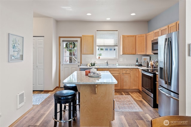 19554 Jensen Way NE, Poulsbo, WA 98370 - kitchen with appliances with stainless steel finishes, light brown cabinets, a sink, a center island, and light wood finished floors