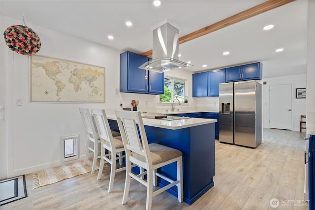 19045 Nutmeg St SW, Rochester, WA 98579 - kitchen with stainless steel fridge with ice dispenser, blue cabinets, island range hood, a breakfast bar, and recessed lighting