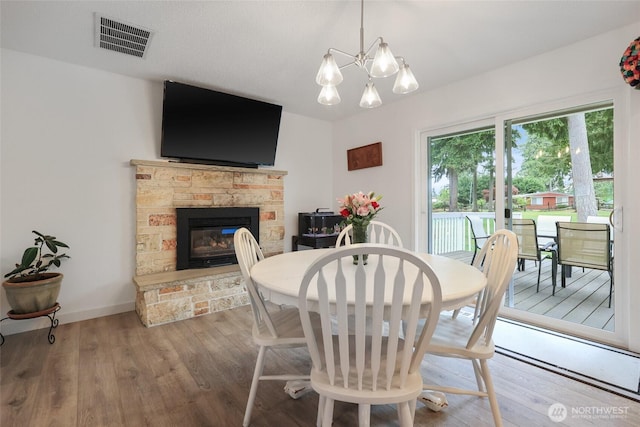 19045 Nutmeg St SW, Rochester, WA 98579 - dining space with wood finished floors, a stone fireplace, a chandelier, and baseboards
