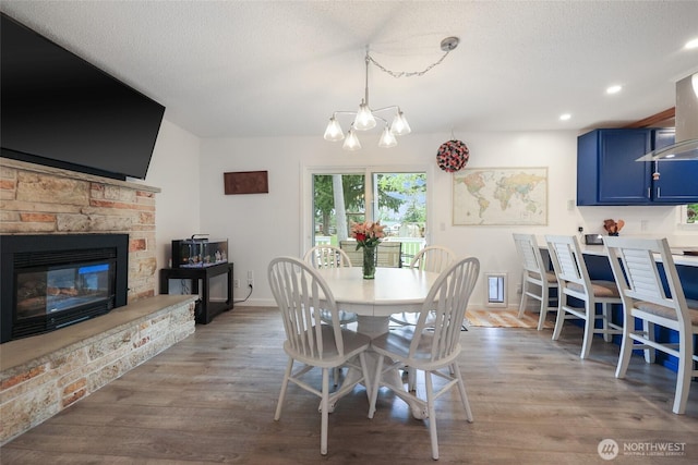 19045 Nutmeg St SW, Rochester, WA 98579 - dining area featuring a chandelier, a fireplace, wood finished floors, baseboards, and recessed lighting