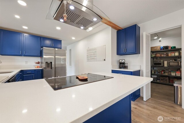 19045 Nutmeg St SW, Rochester, WA 98579 - kitchen featuring stainless steel refrigerator with ice dispenser, blue cabinets, black electric stovetop, range hood, and recessed lighting