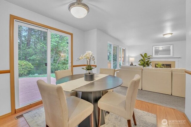 dining space with light wood-style flooring and a fireplace
