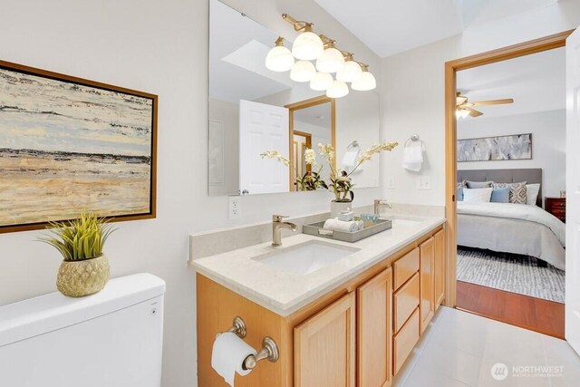 ensuite bathroom featuring ceiling fan, double vanity, toilet, and tile patterned flooring