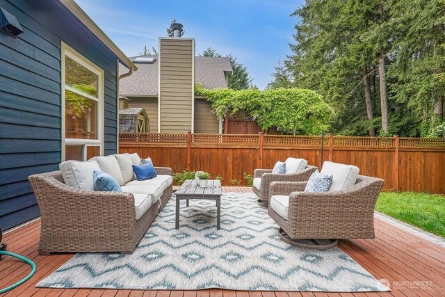 wooden deck with an outdoor living space and a fenced backyard