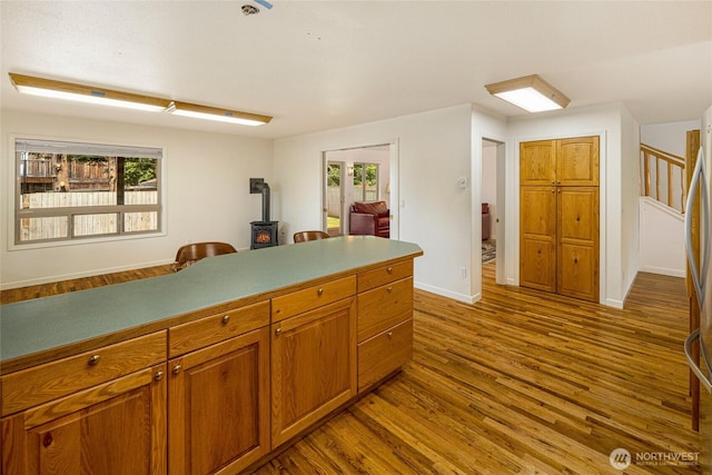 255 Alder St, Orcas Island, WA 98245 - kitchen featuring a wood stove, dark wood-style floors, brown cabinetry, and baseboards