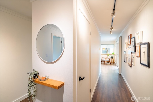 hall with rail lighting, ornamental molding, dark wood-style floors, and baseboards