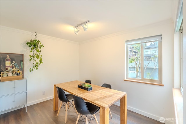 dining room with crown molding, wood finished floors, baseboards, and track lighting