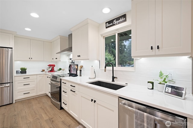 20113 4th Pl S, Des Moines, WA 98198 - kitchen with wall chimney exhaust hood, a sink, appliances with stainless steel finishes, light wood-style floors, and decorative backsplash
