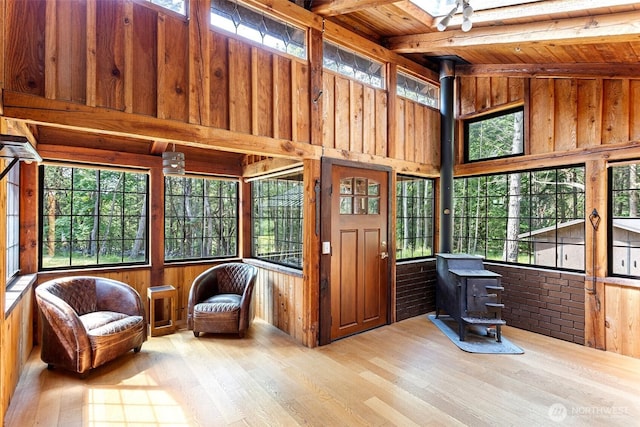 35 N Airport Way, Stuart Island, WA 98250 - sunroom / solarium featuring a wood stove, plenty of natural light, and beam ceiling