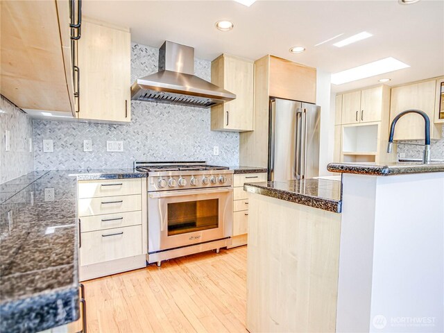 4441 53rd Ave SW, Seattle, WA 98116 - kitchen featuring wall chimney range hood, appliances with stainless steel finishes, light brown cabinets, light wood finished floors, and recessed lighting
