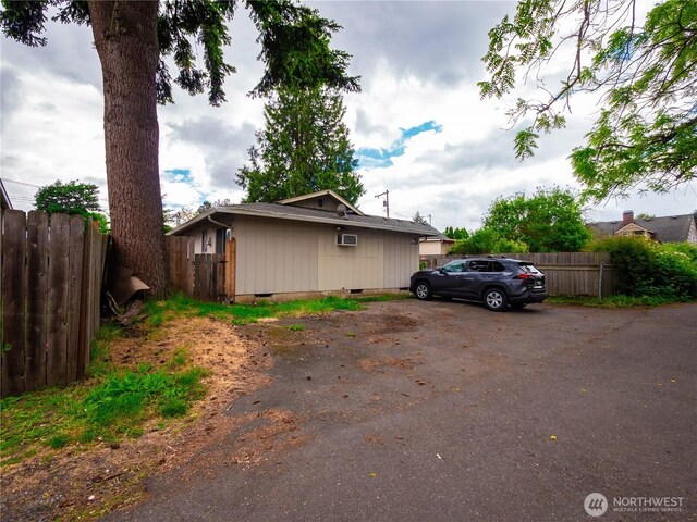 view of side of home featuring crawl space and fence
