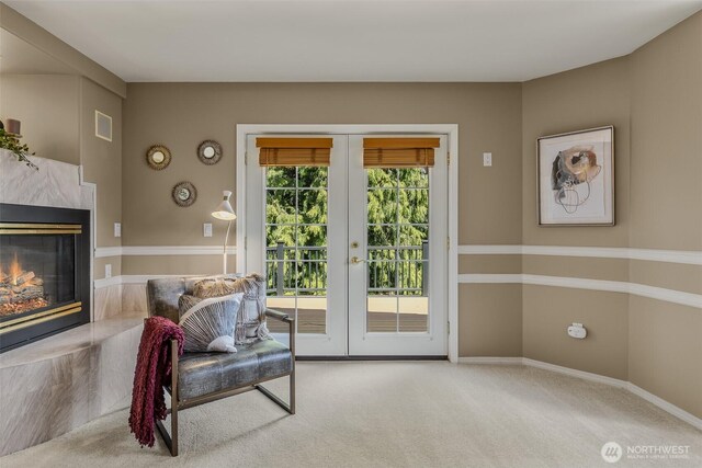 carpeted living area featuring french doors, a fireplace, and baseboards