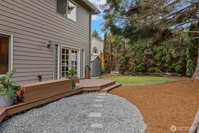 view of yard featuring a deck, fence, and a shed