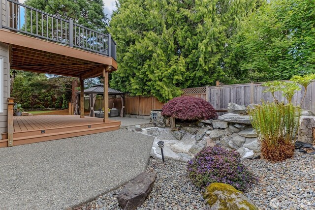 view of yard featuring a gazebo, fence, a wooden deck, and a patio