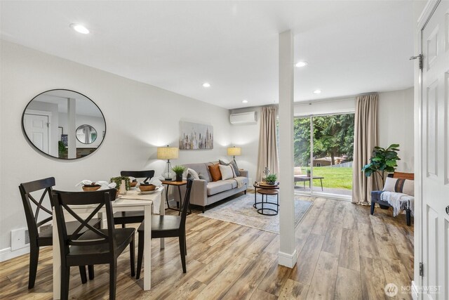 dining area with a wall mounted AC, light wood-style floors, and recessed lighting