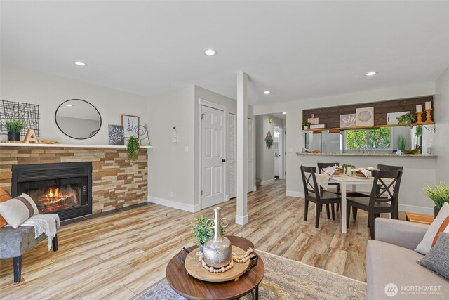living room featuring a glass covered fireplace, wood finished floors, baseboards, and recessed lighting