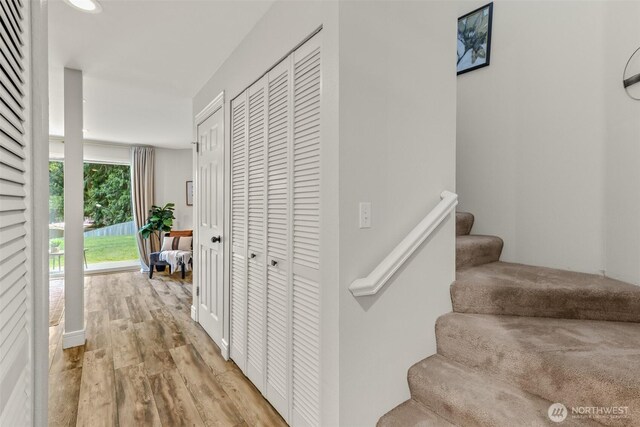 corridor featuring light wood finished floors and stairway