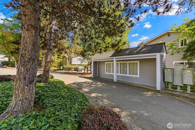 view of front of property featuring asphalt driveway and roof with shingles