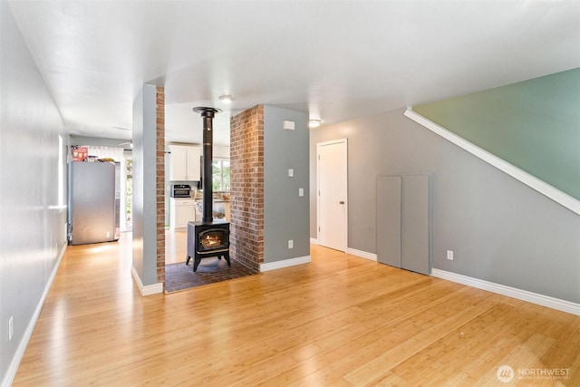 1342 NE Jasmine Ln, Bremerton, WA 98311 - unfurnished living room featuring a wood stove, light wood-type flooring, and baseboards