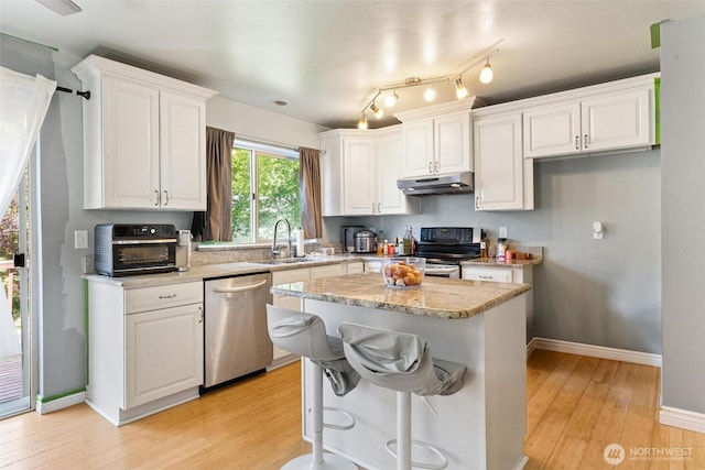 1342 NE Jasmine Ln, Bremerton, WA 98311 - kitchen featuring appliances with stainless steel finishes, under cabinet range hood, a sink, white cabinetry, and light wood finished floors