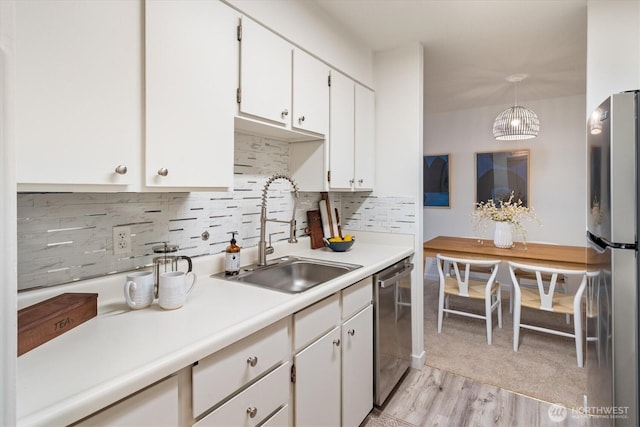4540 8th Ave NE Unit 104, Seattle, WA 98105 - kitchen featuring a sink, stainless steel appliances, light wood finished floors, decorative backsplash, and white cabinets