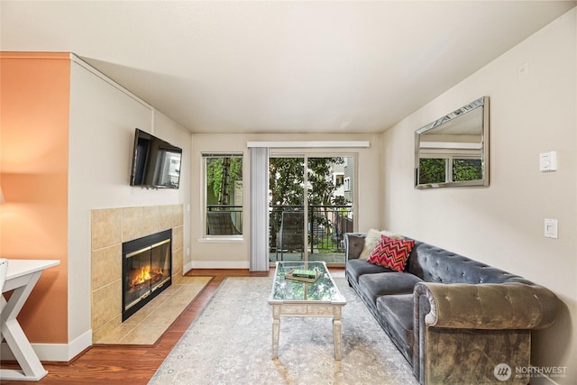living room featuring a tiled fireplace, wood finished floors, and baseboards