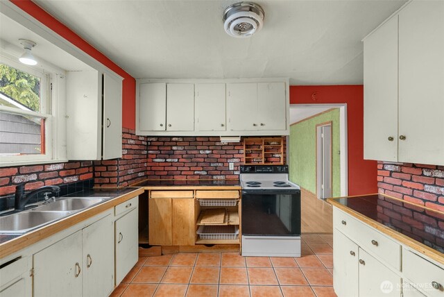 4319 SW Mills St, Seattle, WA 98136 - kitchen with range with electric cooktop, a sink, light tile patterned flooring, and white cabinetry
