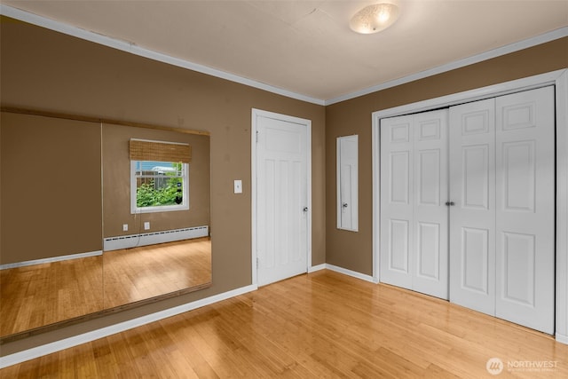 4319 SW Mills St, Seattle, WA 98136 - unfurnished bedroom with a baseboard radiator, light wood-style floors, crown molding, baseboards, and a closet