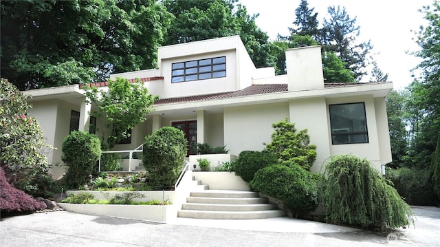 11950 NE 36th Pl, Bellevue, WA 98005 - modern home featuring stucco siding, covered porch, a chimney, and stairway