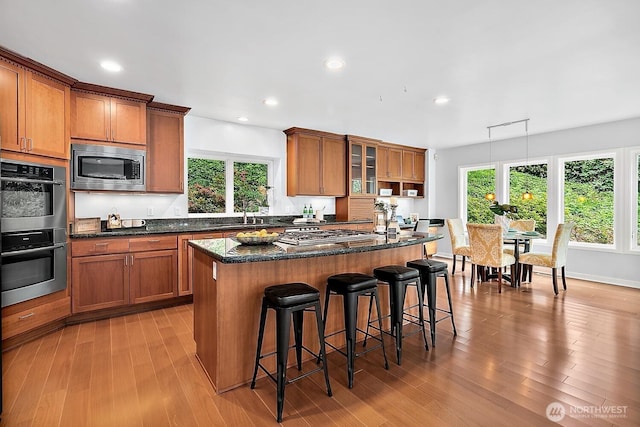 11950 NE 36th Pl, Bellevue, WA 98005 - kitchen featuring appliances with stainless steel finishes, brown cabinets, a kitchen breakfast bar, a kitchen island, and recessed lighting