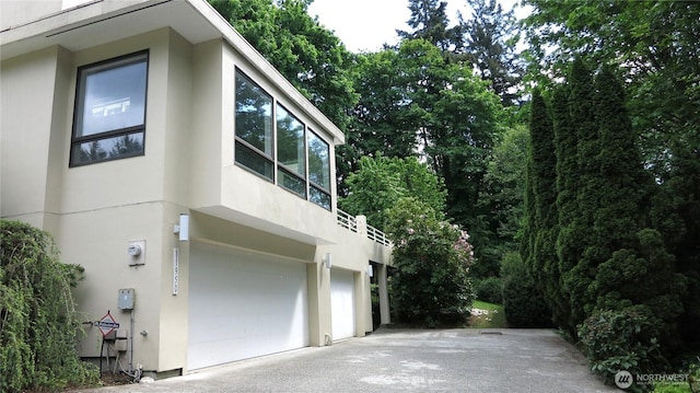 11950 NE 36th Pl, Bellevue, WA 98005 - view of side of property with stucco siding, an attached garage, and driveway
