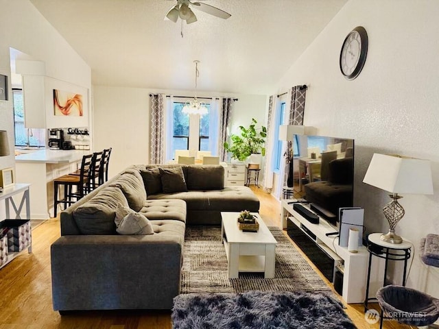living room with lofted ceiling, wood finished floors, a chandelier, and ceiling fan