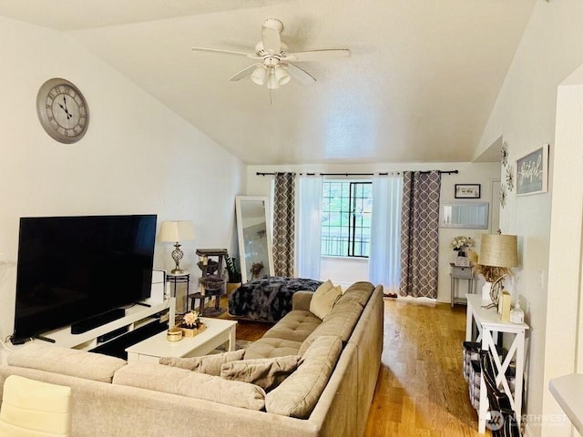 living area featuring vaulted ceiling, light wood finished floors, and a ceiling fan