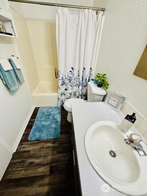 full bathroom featuring a shower with curtain, toilet, wood finished floors, and vanity