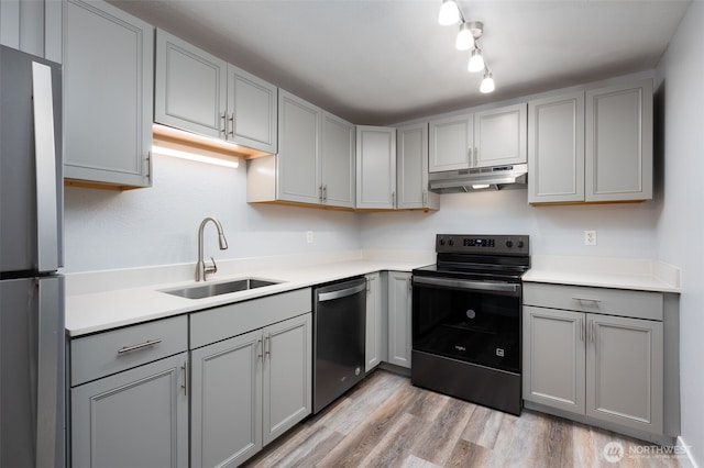 5211 E 96th St, Tacoma, WA 98446 - kitchen with appliances with stainless steel finishes, under cabinet range hood, gray cabinets, a sink, and light wood-style flooring