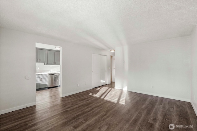 5211 E 96th St, Tacoma, WA 98446 - unfurnished living room featuring a textured ceiling, dark wood-style floors, baseboards, and a sink
