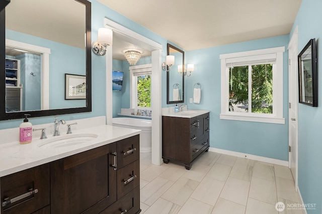 bathroom with healthy amount of natural light, baseboards, and two vanities