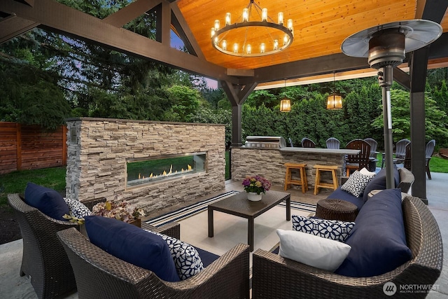 view of patio featuring an outdoor living space with a fireplace, an outdoor bar, a gazebo, area for grilling, and fence