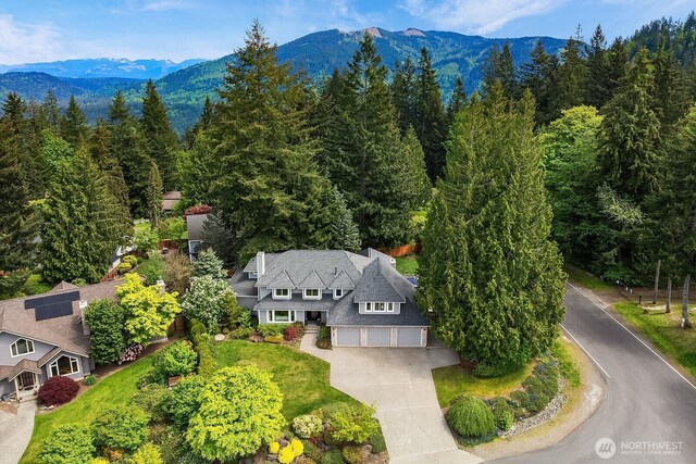 view from above of property with a mountain backdrop and a forest