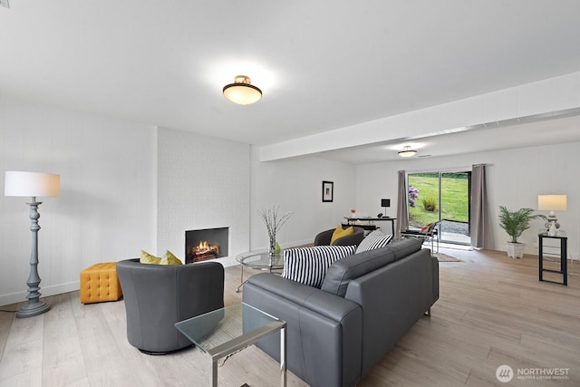 living area with light wood-style flooring, a fireplace, and baseboards