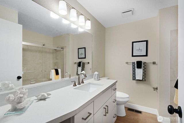 full bath with toilet, wood finished floors, a shower stall, vanity, and baseboards