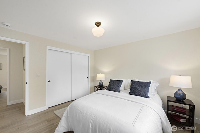 bedroom featuring wood finished floors, a closet, and baseboards
