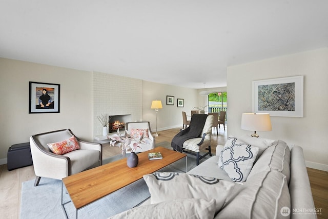 living room with baseboards, wood finished floors, and a brick fireplace