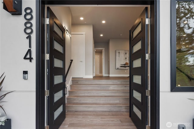 stairs with wood finished floors, recessed lighting, and baseboards
