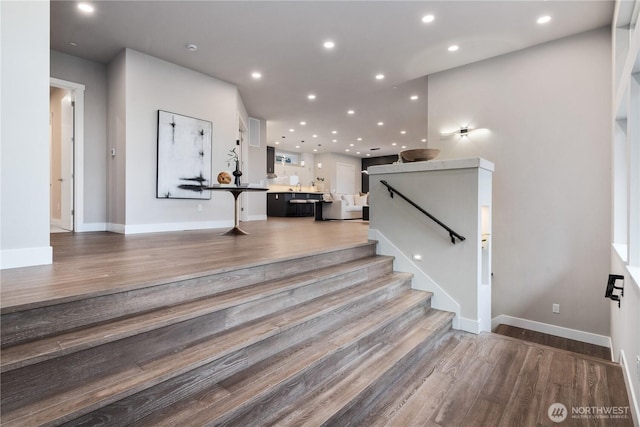 stairway featuring wood finished floors, recessed lighting, and baseboards