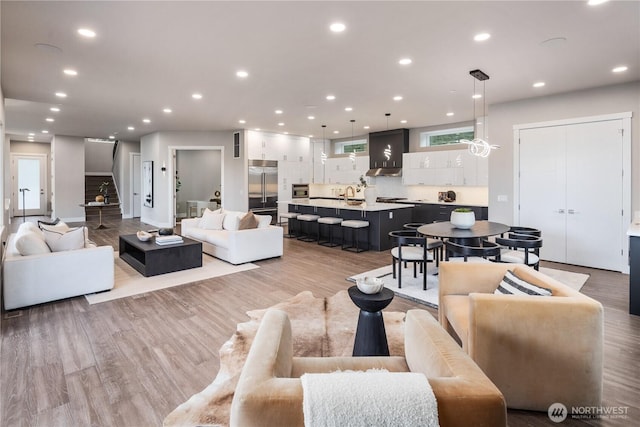living room featuring recessed lighting, light wood-style floors, and stairway